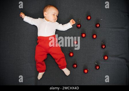 sleeping baby boy lying with Christmas balls. Concept eight months Stock Photo