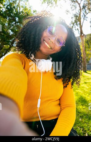 Beautiful woman with glasses curly hair smiling making a self portrait. Stock Photo