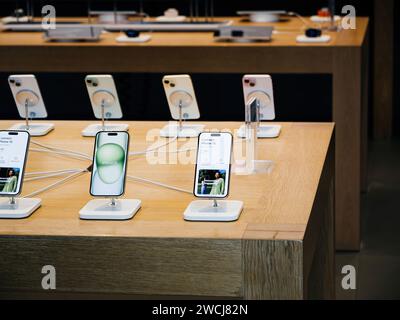 Paris, France - Sep 22, 2023: The new iPhone 15 and 15 Pro debut in an empty Apple Store, sitting charged on a wooden table, marking a subdued sales day Stock Photo