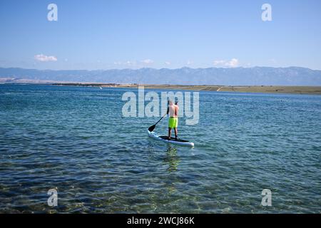a guy is rowing on a paddleboard. Stock Photo