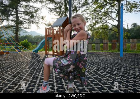 Little happy girl on playground like riding on zipline. Stock Photo