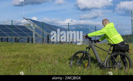 senior man leans on bicycle near solar farm and view of high mountain-krivan slovakia. Stock Photo