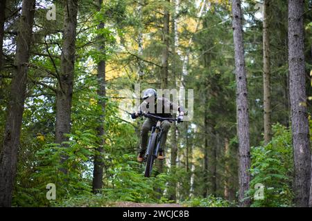 Professional athlete high jump on a mountain bike in the forest, close-up view. Stock Photo