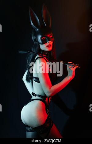 dominatrix mistress girl with sexy ass in harness in Bunny mask with  leather whip for BDSM sex Stock Photo - Alamy
