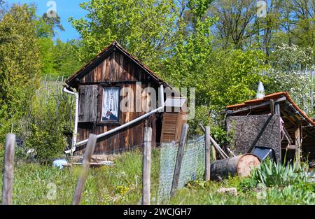 Old wooden hut and old shed in front of bushes and trees in spring in southern Germany Stock Photo