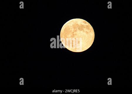 A vibrant full moon against a pitch-black sky Stock Photo