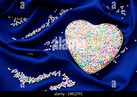 Heart filled with small spheres of different colors on blue background Stock Photo
