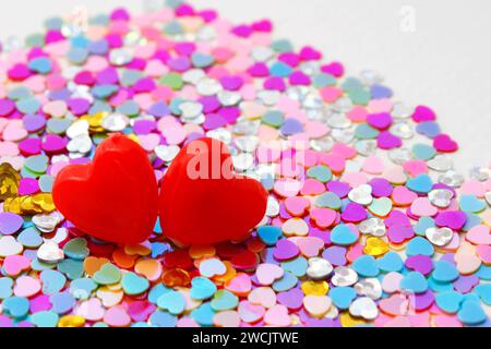 Two red hearts on background of small and colorful shiny hearts Stock Photo