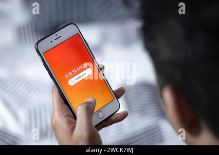 Job Search Concept. Man using smartphone to search job opportunities online from job search app. Stock Photo