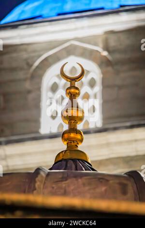 Crescent moon symbol atop a dome of the Yeni Cami or New Mosque illuminated at night before sunrise on the Historic Peninsula in Istanbul, Turkey Stock Photo