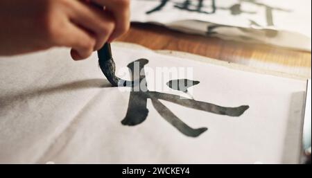 Hands, brush for writing and ancient font for art and script, calligraphy and closeup with alphabet. Japanese, creativity and vintage tools Stock Photo