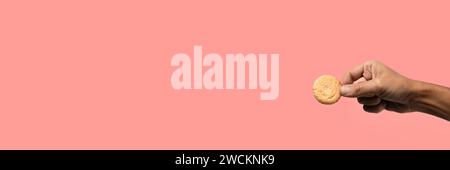 Male hand holding a butter biscuit or cookie. Pink salmon banner. Stock Photo