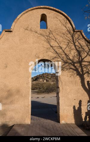 Arched doorway through the protective wall around the Mission San Xavier del Bac frames the Grotto Hill, Tucson Arizona. Stock Photo