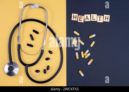 Stethoscope and capsules on yellow and black background. Healthcare, medical exam, insurance,  concept. Stock Photo