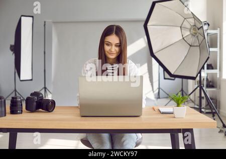 Beautiful woman photographer editing photos on laptop computer in studio Stock Photo