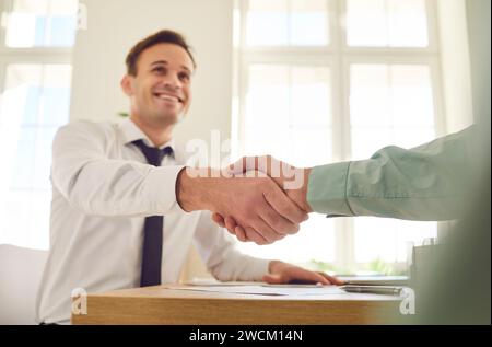 Two business people in office making deal. Two men shaking hands celebrating business achievement. Stock Photo