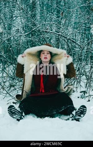 Sitting young woman in sheepskin jacket and with cup of cocoa on color ...