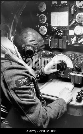 LANCASTER RADIO OPERATOR about 1944.  He is searching frequencies on a Marconi R1155 radio set above which is a Marconi T1154 transmitter.  The operator would normally be wearing gloves at altitude so the large knobs were easier to handle. A Type F morse ket is by his right hand. Stock Photo