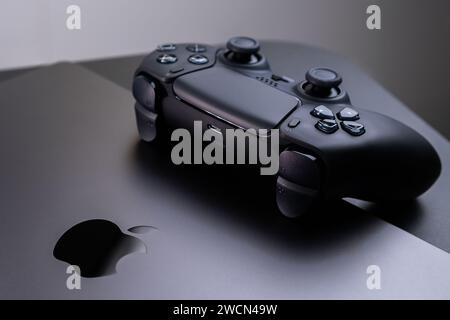 BERLIN , GERMANY - JANUARY 14 2024: A detailed view of the DualSense controller, designed for gaming on an Apple MacBook Pro Space Black. Stock Photo