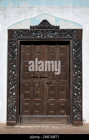 Old brown wooden door with a frame of floral ornaments Stock Photo