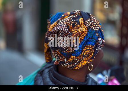 Colourful turban of a black immigrant woman in the old town of Genoa, Italy Stock Photo