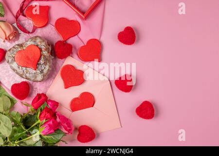 Heart-shaped cake, red hearts and roses around an envelope, Valentine's Day, pink background Stock Photo