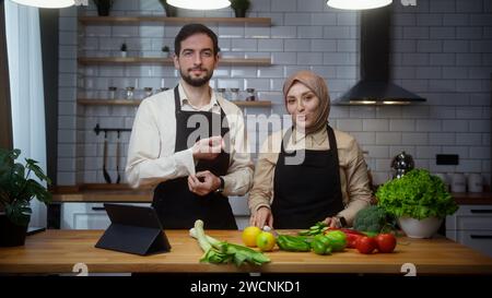 Vlogger professional couple chefs in an apron recording video cooking lesson about vegetarian meal or salad in modern kitchen at home Stock Photo