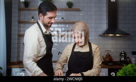 A married couple enjoy conversation in the modern kitchen and prepare healthy vegetarian food preparation together Stock Photo