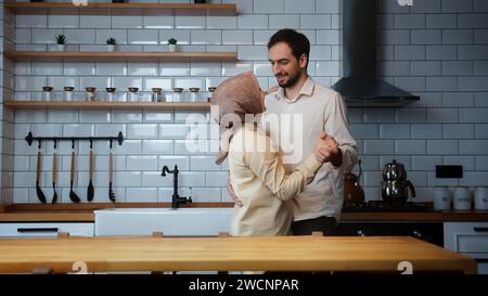 Married happy couple having fun dancing, celebrate their timeless love in the kitchen at home Stock Photo
