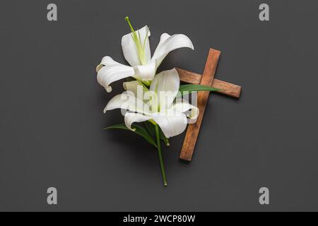 Beautiful lily flowers and cross on black background Stock Photo