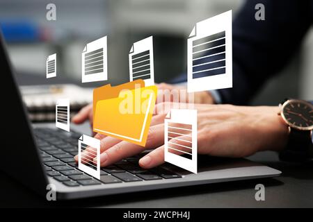 File system. Woman using laptop at table, closeup. Folder and documents over computer Stock Photo