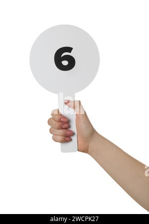 Woman holding auction paddle with number 6 on white background, closeup Stock Photo
