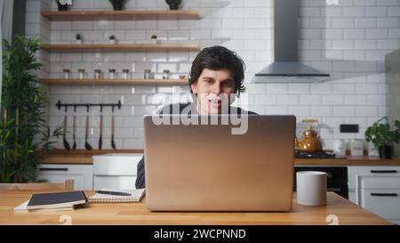 Man working at home in the kitchen working with his laptop. Busy freelancer working on modern tech notebook device Stock Photo
