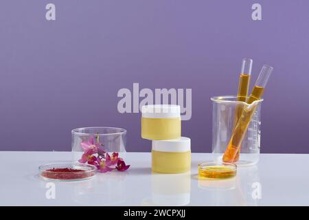 Test tubes of yellow fluid placed in a beaker. Two cosmetic jars stacked on each other with saffron and Crocus flowers beside. Template for mockup you Stock Photo