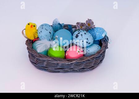 Easter basket with colorful painted eggs, speckled eggs and a small yellow chick. Stock Photo