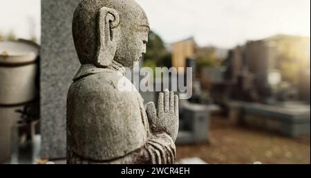 Japan, prayer hands and buddhist stone statue at graveyard for spiritual religion in Tokyo. Jizo, cemetery and gravestone for memorial service Stock Photo