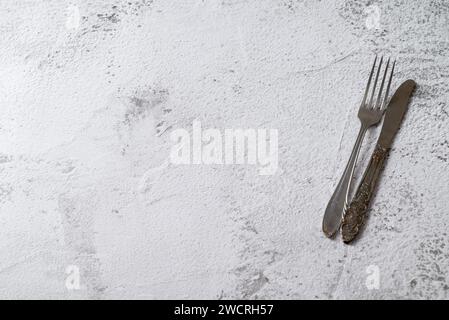 Antique fork and knife on white stone table Stock Photo