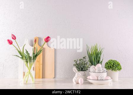 Festive kitchen background for Easter day. Elements of Easter decor, flowers in a vase and pots, eggs and bunny on the kitchen countertop Stock Photo