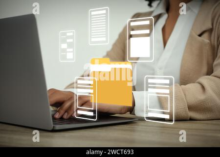 File system. Woman using laptop at table, closeup. Folders and documents over computer Stock Photo
