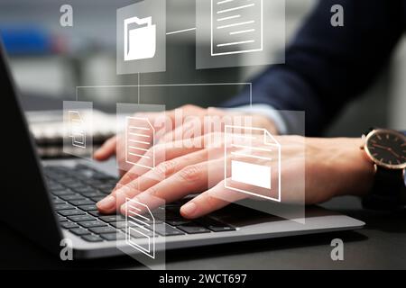 File system. Woman using laptop at table, closeup. Scheme with folder and documents over computer Stock Photo