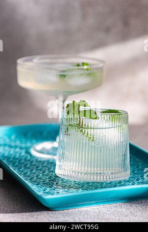 Two elegant cocktails on a blue tray with a textured background, one garnished with mint Stock Photo