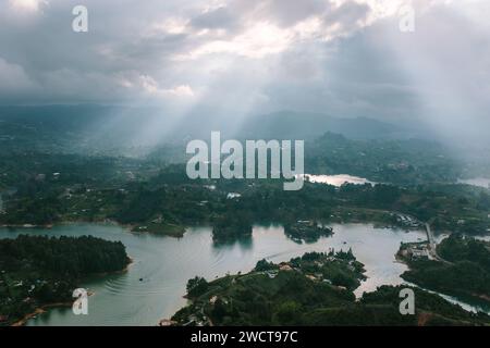 Sunbeams breaking through clouds over a lush, mountainous landscape with a winding river Stock Photo