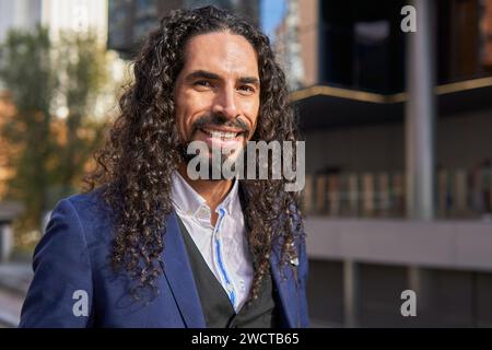 Portrait of a confident mature Latin businessman with long curly hair, smiling in an urban looking at camera Stock Photo
