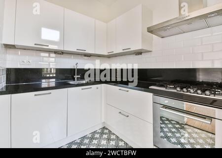 A sleek modern kitchen featuring glossy white cabinets, black granite countertops, and stainless steel appliances. Stock Photo