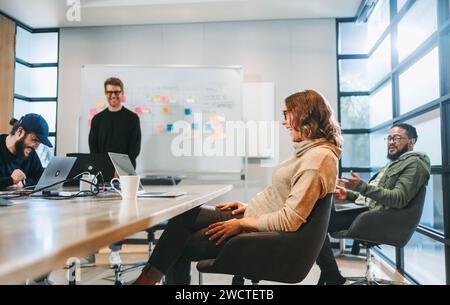 In a boardroom, business men and women collaborate and brainstorm, discussing ideas for a project. The team is happy and professional, displaying team Stock Photo