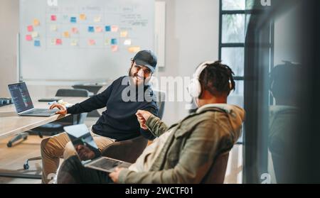 Two men celebrating their successful ideas. Coding and programming together, smiling and working on software development. A happy, creative team in a Stock Photo