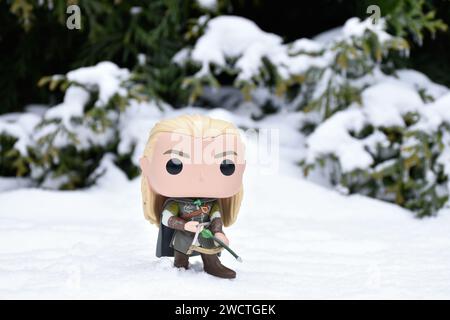 Funko Pop action figure of elf Legolas from fantasy movie The Lord of the Rings. Warrior holding bow and arrow. Winter forest, snow, green woods. Stock Photo