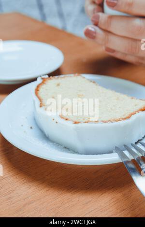 vertical image of pudding with cream, on plate on table in cafe, with unrecognizable woman sitting in background holding cup of coffee, cafe concept, Stock Photo