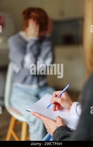 the hand of a psychologist writes down an anamnesis. client in the background Stock Photo