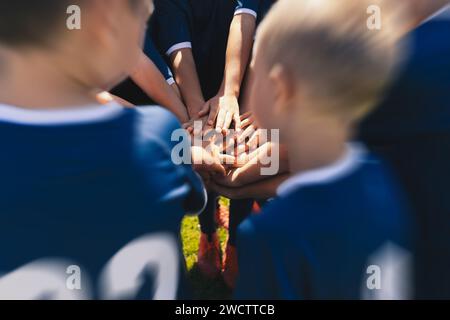 Happy Children Sports Team Stacking Hands. Kids Having Fun During Outdoor Physical Education Practice. Little Boys in Sports Clothes at Soccer Field Stock Photo